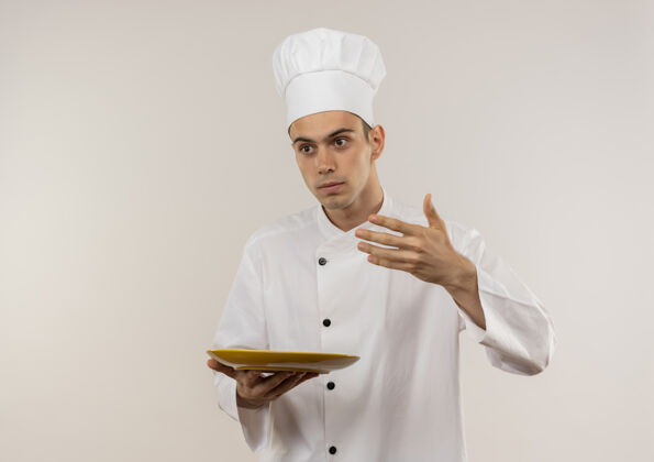 看看着旁边穿着厨师制服的年轻男厨师 他手里拿着盘子里的东西 站在孤零零的白墙上盘子厨师厨师