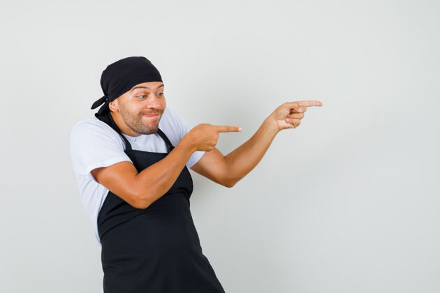 职业面包师穿着t恤 围裙指向侧面 看起来很活泼制服男性工作