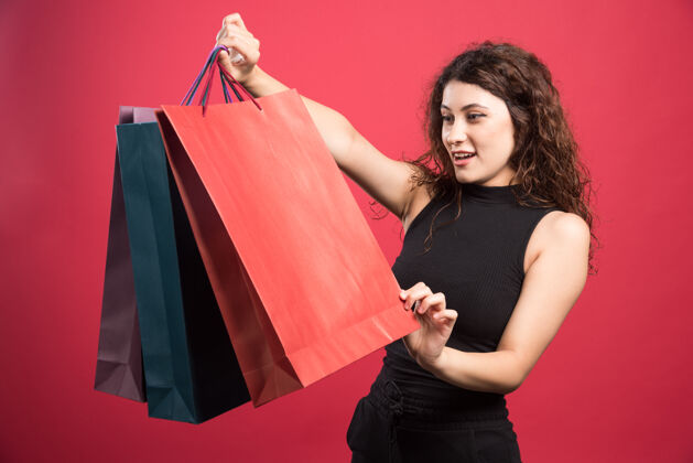 购买一个女人在看她在红色背景上买的新衣服购物女性年轻人