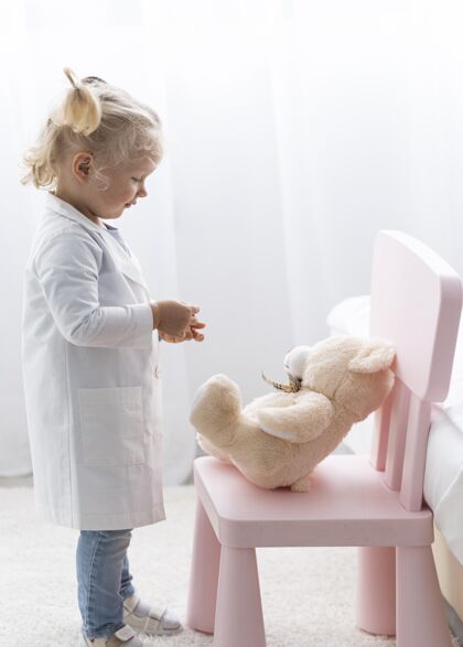 研究侧视图可爱的幼儿与实验外套和泰迪熊泰迪熊研究学习