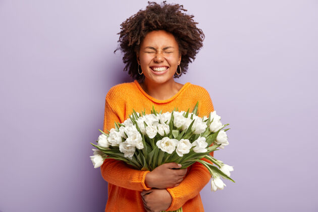 庆祝摄影棚拍摄的喜出望外的黑皮肤女性闭上眼睛从积极的情绪 微笑广泛照片情绪化植物