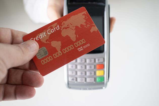 手机手持红色信用卡的人 背景是模糊的支付终端购买机器商业