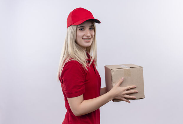 盒子微笑的小女孩穿着红色t恤 戴着帽子 戴着牙套 在孤立的白色背景下拿着盒子戴着帽子白色