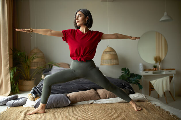 锻炼人 活动 健康和活力的概念时尚的赤脚年轻女子在家里锻炼 在卧室做vinyasa流瑜伽瑜伽战士灰色