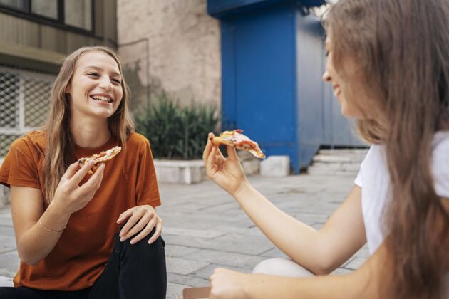 娱乐年轻女人一起吃比萨饼当地假日积极休闲