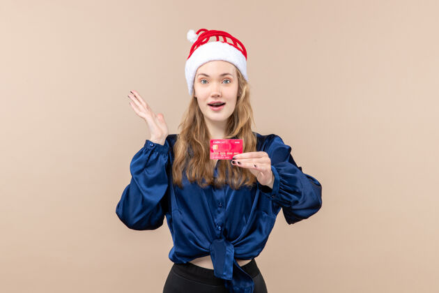 情感正面图年轻女性手持粉色背景的红色银行卡过节照片新年钱情圣诞节抱着微笑