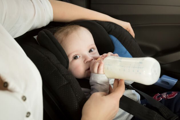 乘客母亲在车里用奶瓶喂婴儿的特写照片保健座位责任
