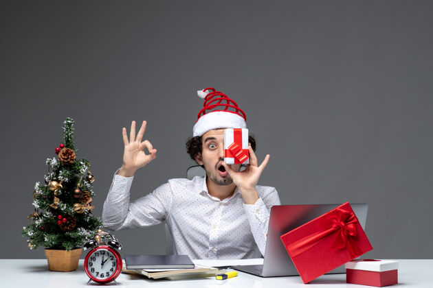艺人圣诞节心情与有趣的商人与圣诞老人的帽子提高他的礼物 他的脸上 使眼镜的姿态在白色背景圣诞老人眼镜圣诞节
