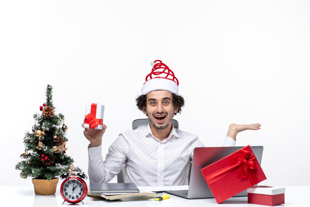 圣诞老人圣诞气氛与微笑的年轻商人圣诞老人帽子和举行他的礼物愉快的白色背景人快乐年轻人