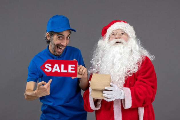 圣诞老人圣诞老人的正面图 男性信使手持销售横幅 灰色墙上挂着食品包装圣诞包裹人