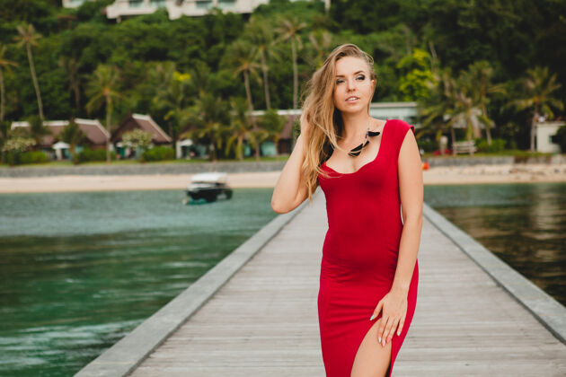激情年轻漂亮迷人的女人独自站在豪华度假酒店的码头上 暑假 红色长裙 金色头发 性感服装 热带沙滩 诱惑 性感 微笑风女人优雅