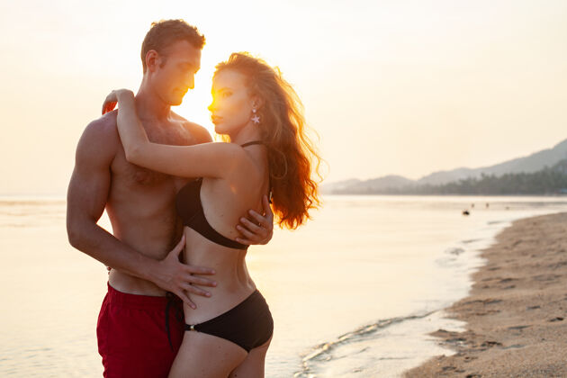 浪漫年轻性感浪漫的情侣在夏天的沙滩上快乐地穿着泳装玩女性男朋友看