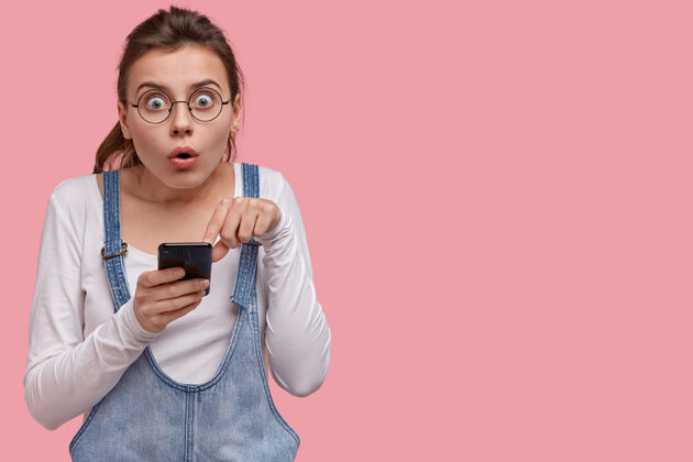 技术情绪激动惊讶的年轻女子不敢相信网上商店的销售和折扣 指着智能手机屏幕 对收到的通知感到惊讶互联网电话沮丧