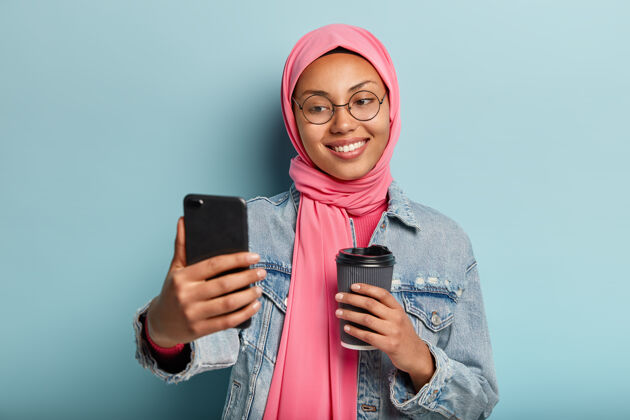 阿拉伯微笑的阿拉伯女孩在手机上自拍的画像咖啡面纱手机