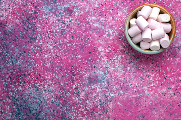 蛋白酥皮粉红色表面上的圆锅里甜蜜可口的棉花糖俯视图生的锅桌子