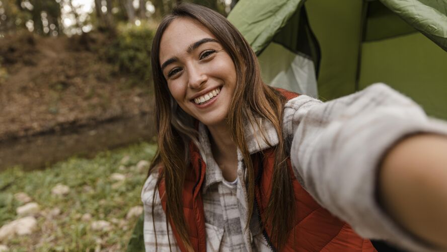 旅行者快乐的野营女孩在森林里自拍旅行木材旅游