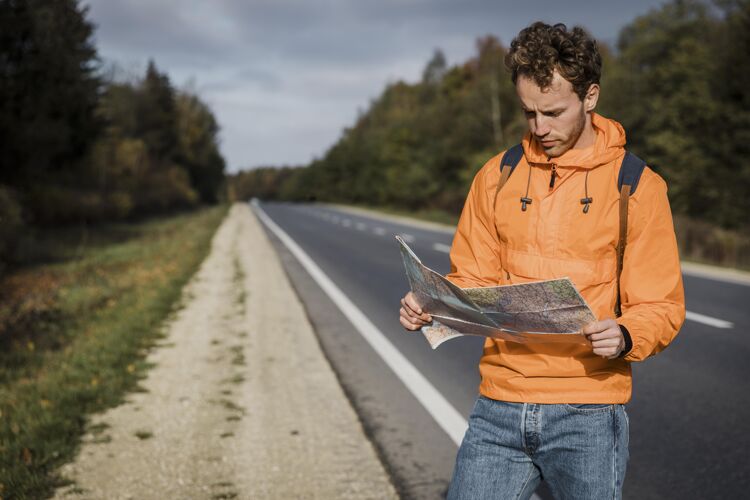 男性手持地图坐在路边的男人的正视图冒险户外航行