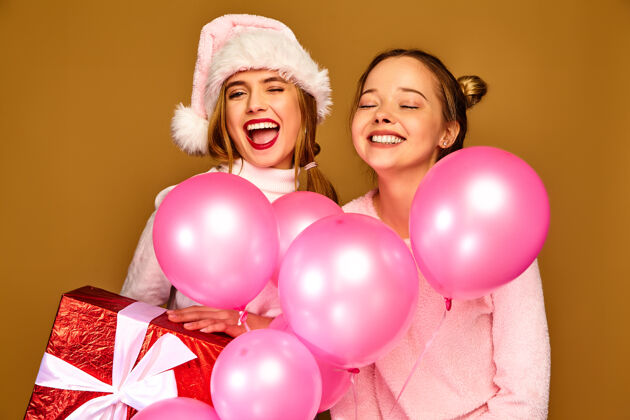 人们圣诞节带着大礼盒和粉色气球的模特们青春性感庆祝