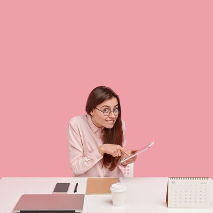 智能手机开朗的黑发女青年在touchpad上做网上订票 做行政经理工作姿势桌子