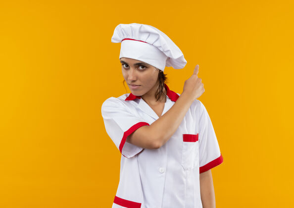 厨师年轻的女厨师穿着厨师制服 点着背对着隔离的黄色墙壁 留着临摹的空间年轻女厨师
