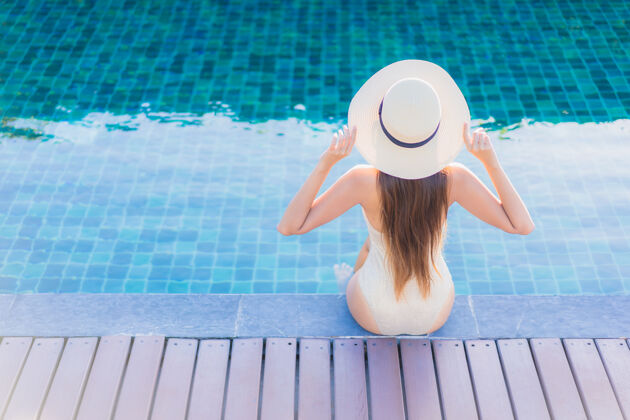 享受美丽的亚洲年轻女子在度假酒店的室外游泳池周围放松的肖像放松女性游泳