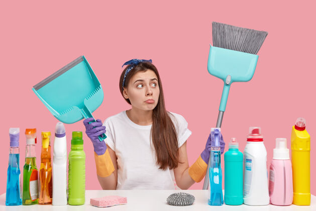 心烦整洁和清洁的概念迷人的黑发女人戴着头带 神情沮丧 拿着扫帚和勺子 独自打扫房间清洁职业清洁剂