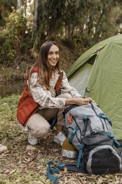 树木快乐的野营女孩在森林里寻找背包木材探险度假