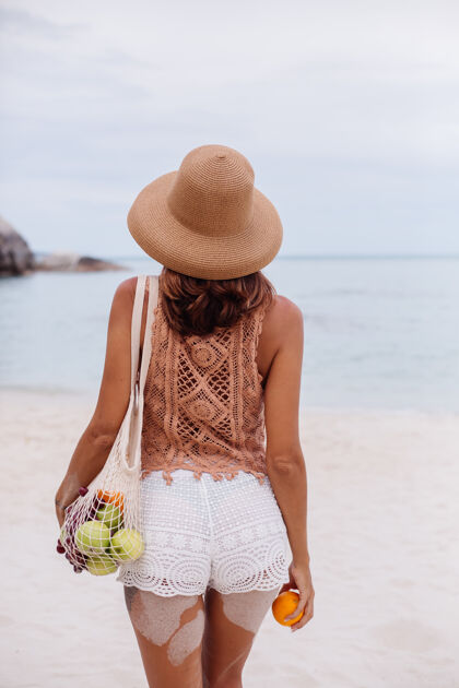 夏季年轻漂亮的白种人 皮肤黝黑 穿着针织衣服 戴着帽子在沙滩上健康面料沙滩