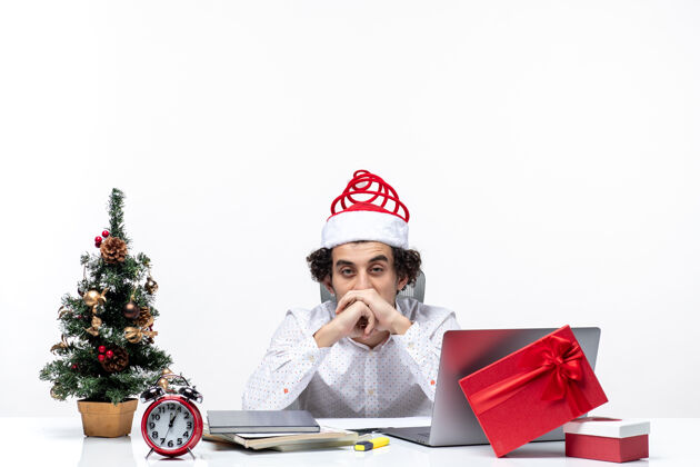 人新年心情带着年轻商人带着搞笑的圣诞老人帽子 感觉办公室里的一切都在白色背景下筋疲力尽帽子圣诞节风