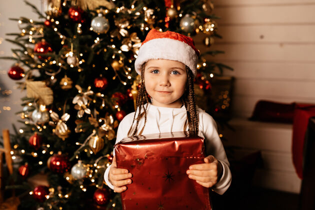 庆祝迷人的欧洲女孩拿着礼物在圣诞树在家里圣诞圣诞老人快乐
