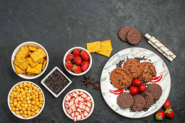 香料俯瞰美味的巧克力饼干和不同的零食在黑暗的桌子上甜甜的饼干茶书桌碗水果