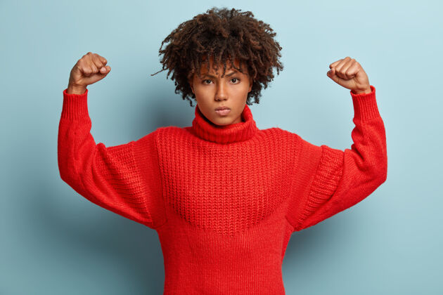 皱眉愤怒的非洲裔美国妇女的照片保持手臂举起 握紧拳头 显示肌肉不高兴愤怒水平