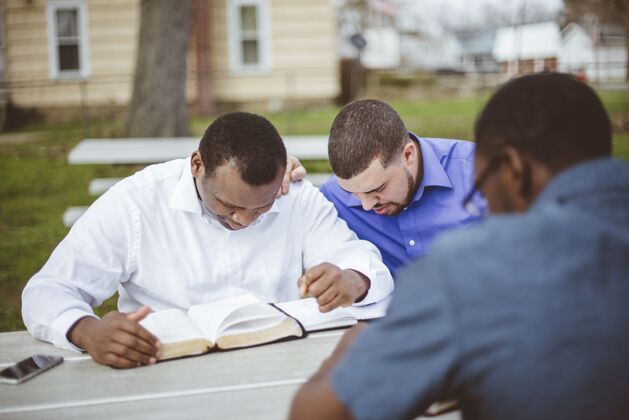 阅读一群不同的人坐在桌边读圣经圣经宗教多样性
