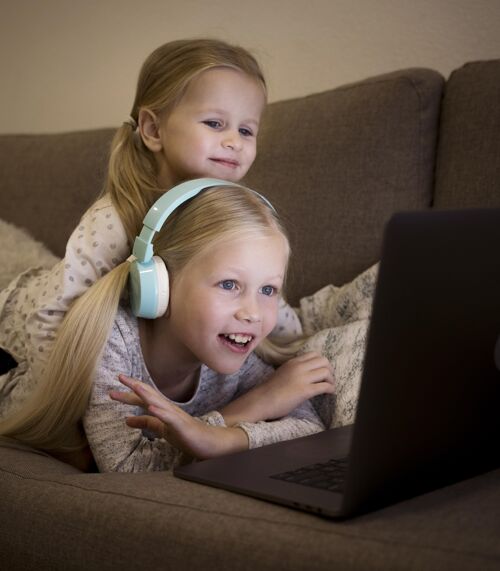 女孩美丽的姐妹们在家使用科技孩子垂直笔记本电脑