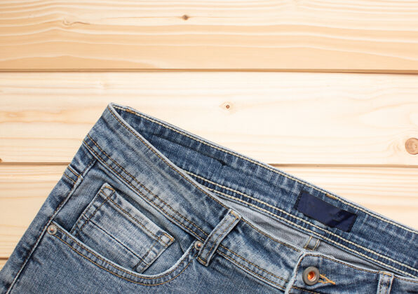 制造蓝色牛仔裤的木质背景纹理牛仔布顶视图磨损服装面料
