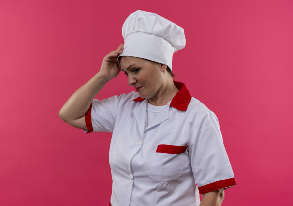 女困惑的中年女厨师穿着厨师制服把手放在孤立的粉红色墙上的前额上前额制服放