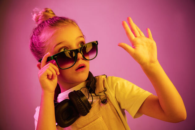 可爱霓虹灯肖像 戴着耳机享受音乐的吓坏了的年轻女孩迪斯科耳机太阳镜