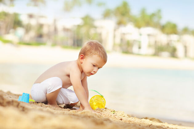 海滩一个在海滩度假的两岁男孩男孩阳光沙滩
